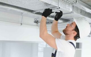 Construction worker installing HVAC duct system