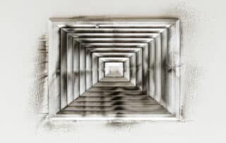 Close-up of a dirty ceiling air vent covered in dust and black residue, showing the need for professional air duct cleaning and maintenance.