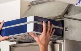 Person replacing air conditioner filter at home