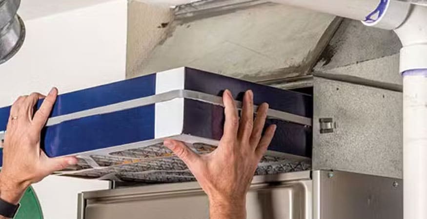 Person replacing air conditioner filter at home