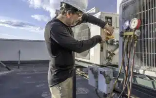 Seasonal HVAC maintenance checklist for Colorado homes showing an HVAC technician checking mini split air conditioner amps with a meter, highlighting routine inspections, electrical testing, efficiency checks, and preventive care for reliable heating and cooling.