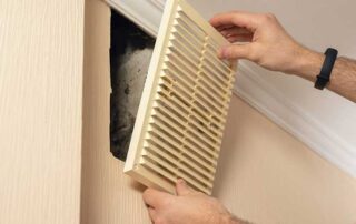 Technician installing a wall air vent cover during HVAC maintenance. Image represents inspection and cleaning to prevent common types of mold in air ducts, including black mold and mildew, which can affect indoor air quality and system efficiency.