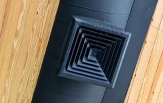 Black ceiling air vent on wooden panel